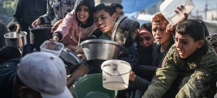 Niños y jóvenes se esfuerzan por alcanzar una porción de la comida que llega con la ayuda humanitaria a la Franja de Gaza.